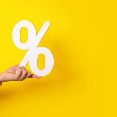 En hand som håller i en procentsymbol på en gul bakgrund
