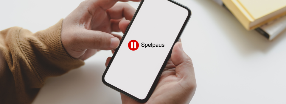 Händer som håller i en mobiltelefon med spelpaus logga