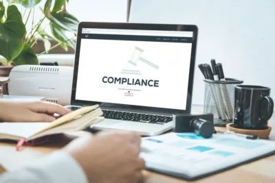 Compliance, on a laptop set on a busy desk.