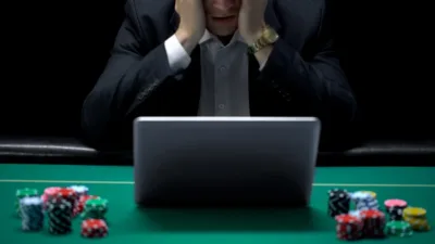 Poker player in front of laptop, losing online game