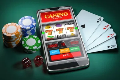 Mobile phone showing online casino site, poker chips and playing card displayed on table.