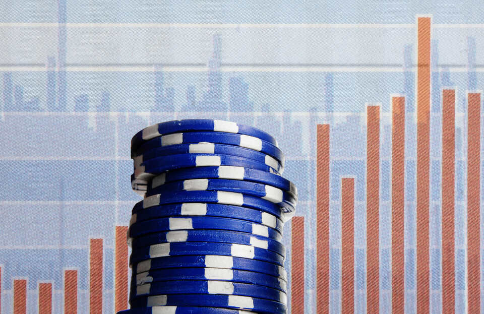 Casino chips stacked in front of a financial graph.