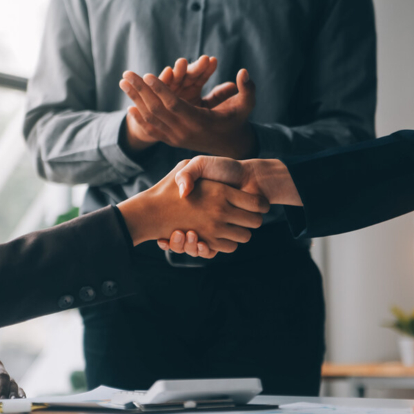 2 people shaking hands in a meeting