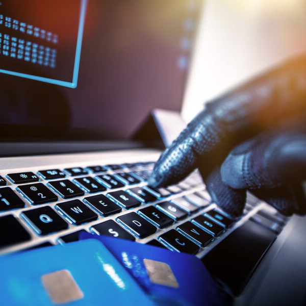 a gloved person using credit cards with a computer